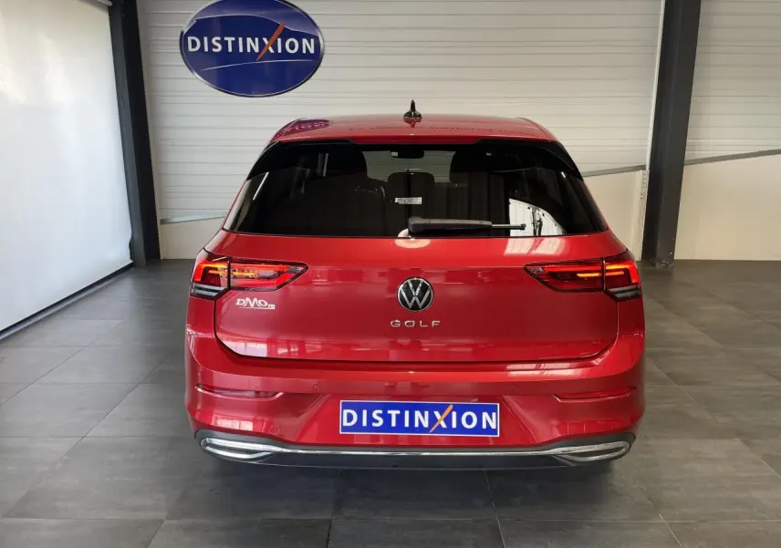 Vue arrière d'une Volkswagen Golf rouge métallisée 2022 avec feux LED et logo distinctif dans un showroom.