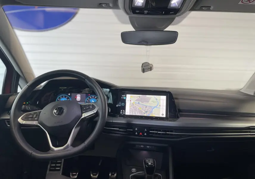 Vue frontale intérieure du tableau de bord et volant cuir noir de la Volkswagen Golf 1.5 TSI Active 2022 avec écran tactile et levier de vitesses manuel.