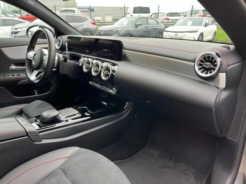 Intérieur côté passager de la Mercedes CLA Shooting Brake 250 AMG Line 2022 avec tableau de bord noir et surpiqûres rouges.