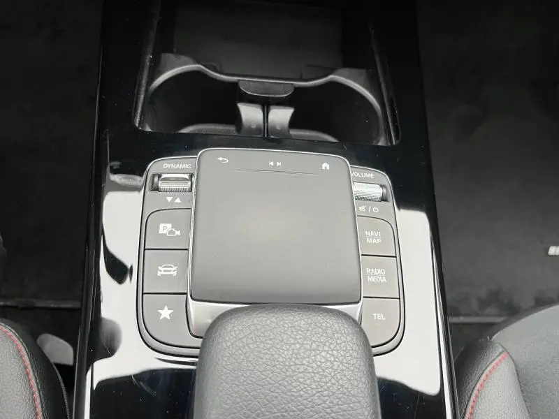 Gros plan sur la console centrale noire brillante avec pavé tactile et commandes du système multimédia d'une Mercedes CLA Shooting Brake AMG Line.