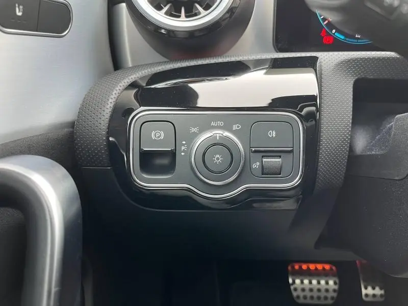 Gros plan sur la commande d’éclairage noire brillante du tableau de bord intérieur de la Mercedes CLA Shooting Brake gris montagne.