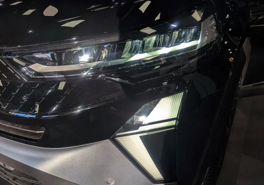 Gros plan sur le phare avant droit du Renault Captur E-TECH noir étoilé, soulignant ses feux LED modernes et détails anguleux.