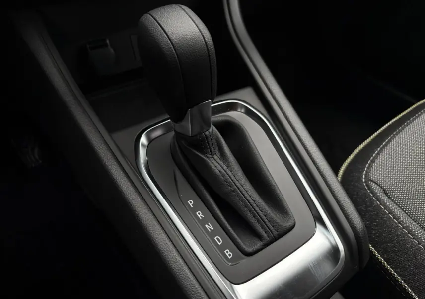 Gros plan sur le levier de vitesses automatique noir du Renault Captur 2025, avec coutures apparentes et console sombre.