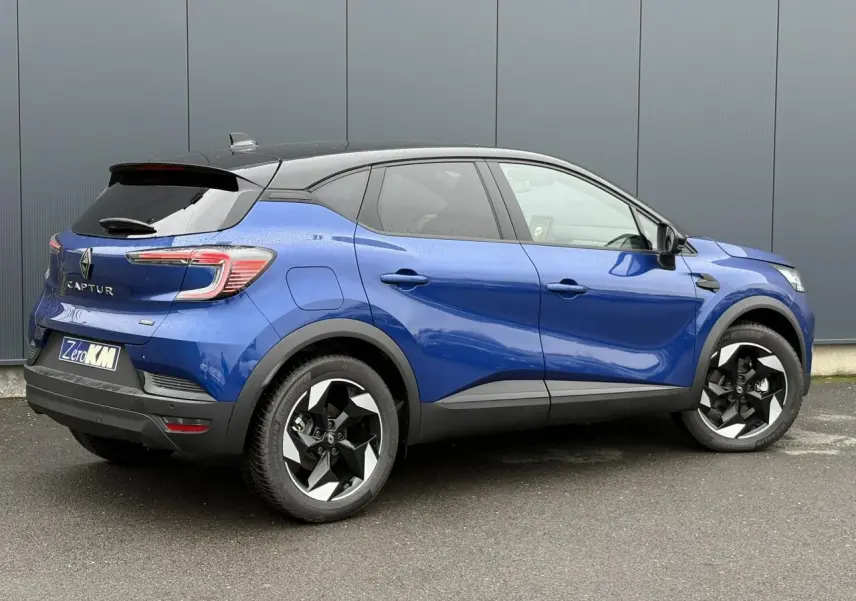 Vue 3/4 arrière droite du Renault Captur 2025 bleu Iron avec jantes aluminium noires et toit biton noir.