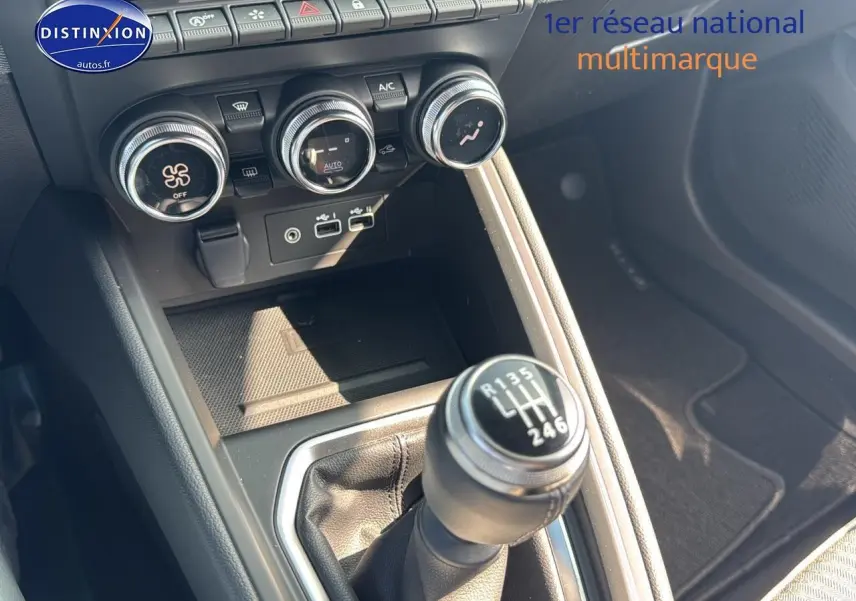 Gros plan sur la console centrale noire de la Renault Clio V avec levier de vitesse manuel et commandes de climatisation.