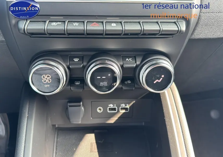 Détail de la console centrale noire de la Renault Clio V avec commandes de climatisation et ports USB visibles.
