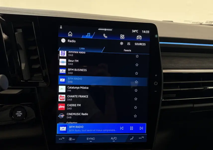 Vue rapprochée de l’écran tactile central du tableau de bord du Renault Espace blanc, affichant les stations radio.