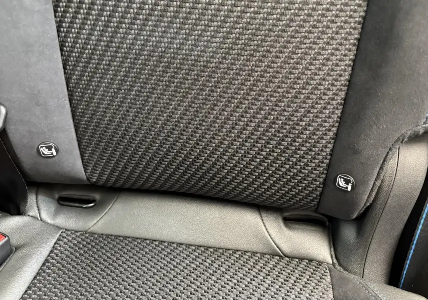 Gros plan sur le tissu noir texturé et les fixations Isofix du siège arrière d'un Renault Espace blanc esprit Alpine 2025.
