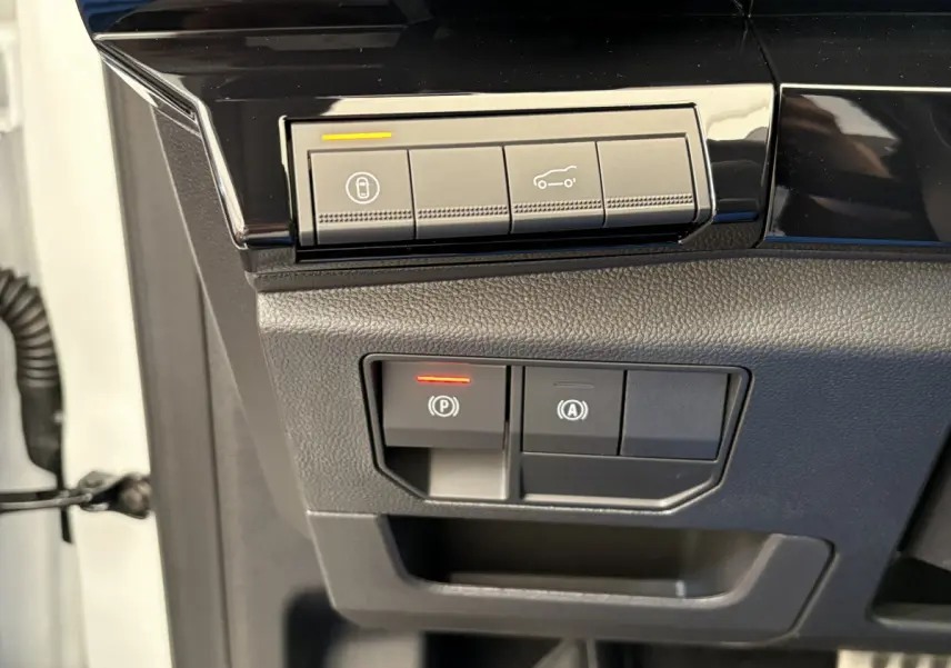 Gros plan sur les commandes de verrouillage et ouverture du coffre du Renault Espace blanc, côté conducteur.