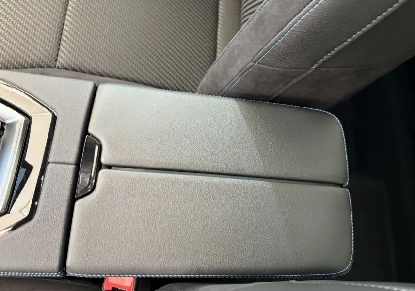 Gros plan sur l'accoudoir central en cuir noir avec surpiqûres bleues dans l'habitacle du Renault Espace blanc.