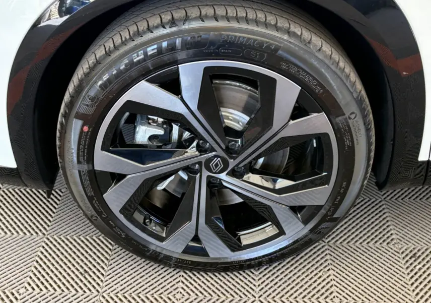 Gros plan sur la roue avant droite de la Renault Espace blanche, jante alliage noire et argentée au design moderne.