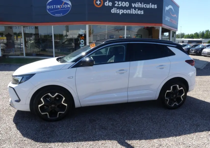 Opel Grandland blanc métallisé vu de profil droit, toit noir brillant et jantes alliage noires.