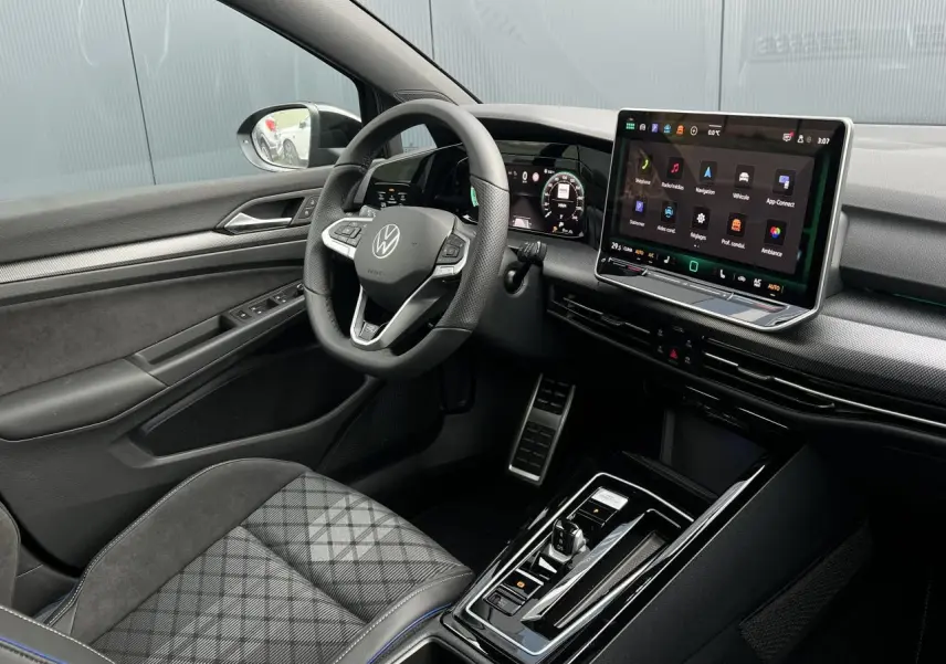 Vue intérieure côté conducteur de la Volkswagen Golf VIII R-Line 2026, avec tableau de bord numérique et sellerie noire à motifs.