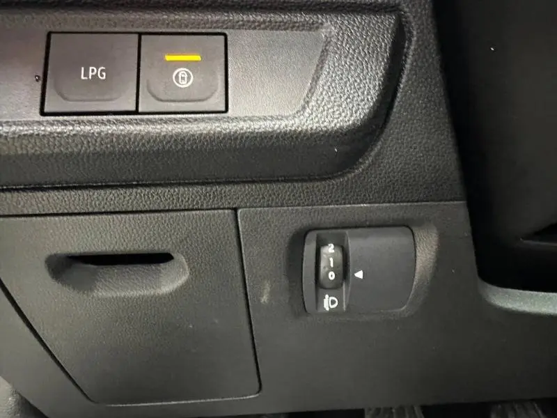Gros plan sur les commandes intérieures du Dacia Jogger 2025, avec bouton LPG et réglage des phares sur plastique noir.