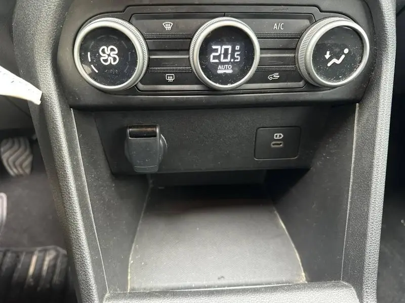 Gros plan sur la console centrale du Dacia Jogger 2025 montrant les commandes de climatisation et une prise USB.