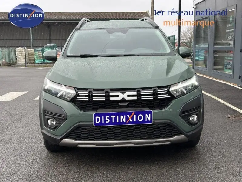 Vue avant d'une Dacia Jogger 2025 kaki lichen avec calandre noire et logo distinctif, stationnée sur un parking.