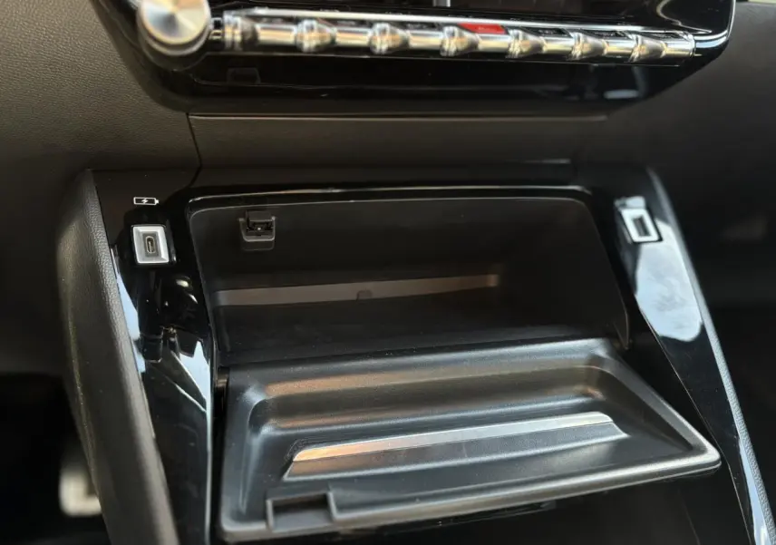 Gros plan sur la console centrale noire brillante du Peugeot 2008 GT 2021 avec prises USB et rangement ouvert.