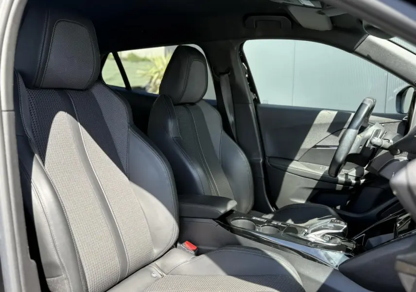 Intérieur avant du Peugeot 2008 GT 2021 en tissu et TEP noir avec console centrale et volant compact cuir.