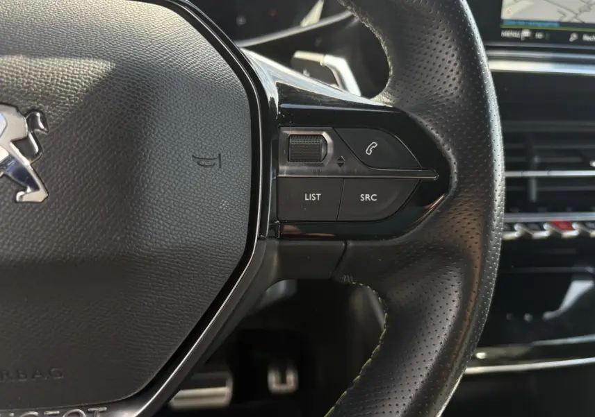 Gros plan sur le volant cuir perforé noir avec commandes multimédia et surpiqûres vertes du Peugeot 2008 GT 2021.