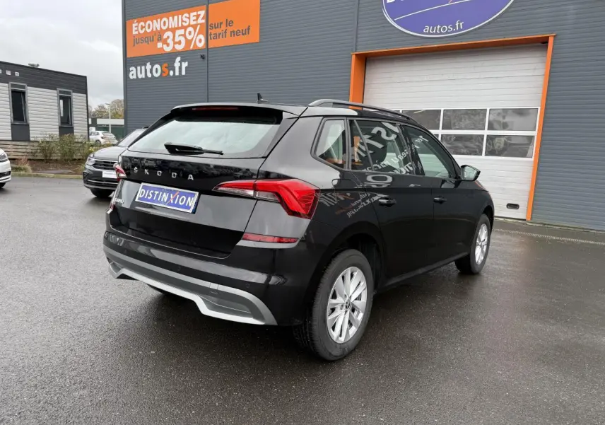 Vue 3/4 arrière droite d'un Skoda Kamiq noir Magic nacré avec feux arrière LED et jantes argentées sur parking.