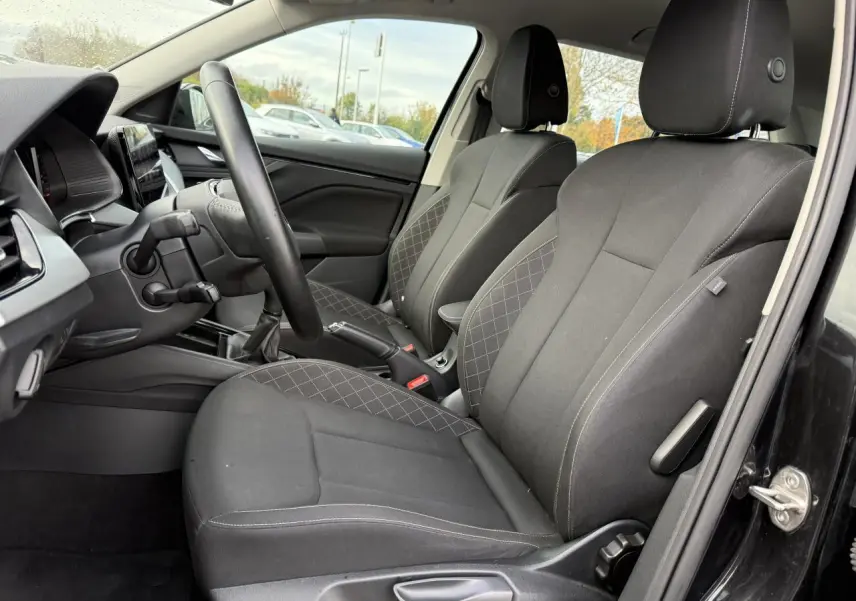 Intérieur du Skoda Kamiq 2023 en vue latérale côté conducteur, sièges tissu noir avec surpiqûres contrastées.