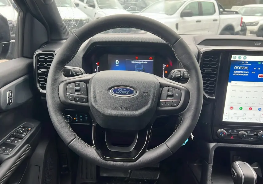 Vue intérieure centrée sur le volant noir du Ford Ranger 2025 avec tableau de bord digital et écran tactile couleur.