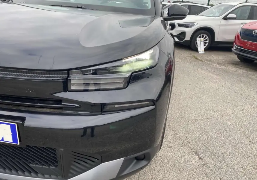 Gros plan sur l'avant droit de la Citroën C4 noire Perla Nera avec ses phares LED allumés et calandre moderne.