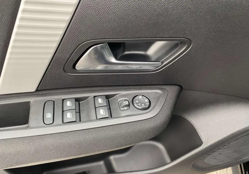 Gros plan sur la poignée intérieure et les commandes des vitres côté conducteur de la Citroën C4 noire Perla Nera.