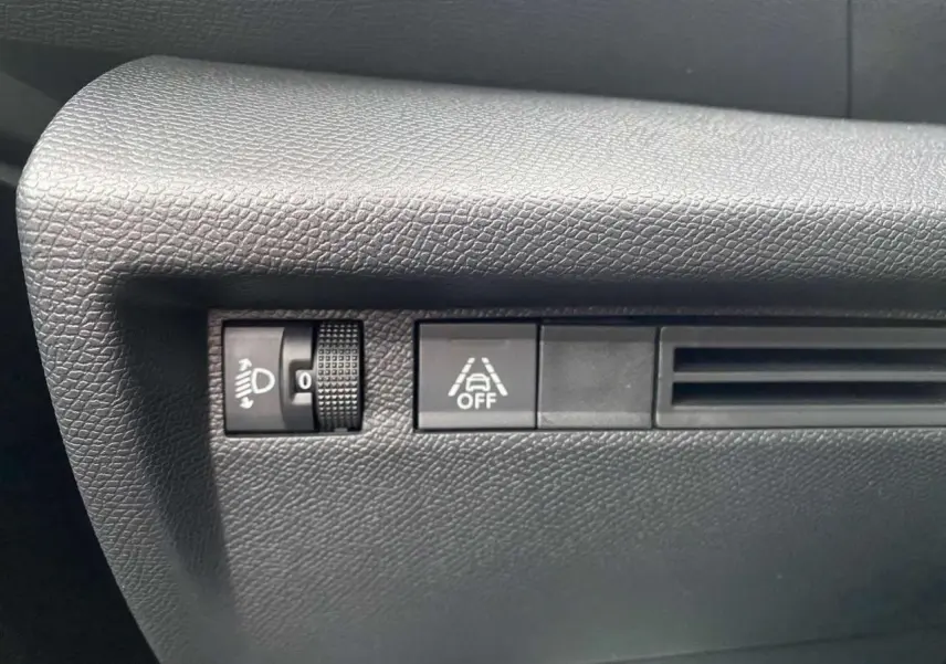 Gros plan sur les commandes de réglage des phares et désactivation de l'assistance de maintien de voie dans une Citroën C4 hybride 2025.
