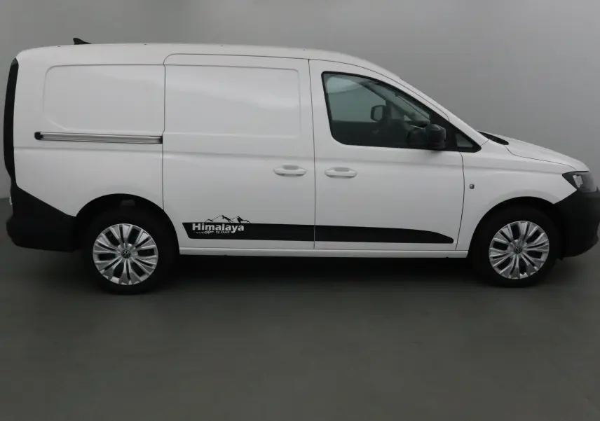 Profil droit d'un Volkswagen Caddy Maxi blanc avec logo Himalaya et jantes argentées, intérieur visible par la vitre.