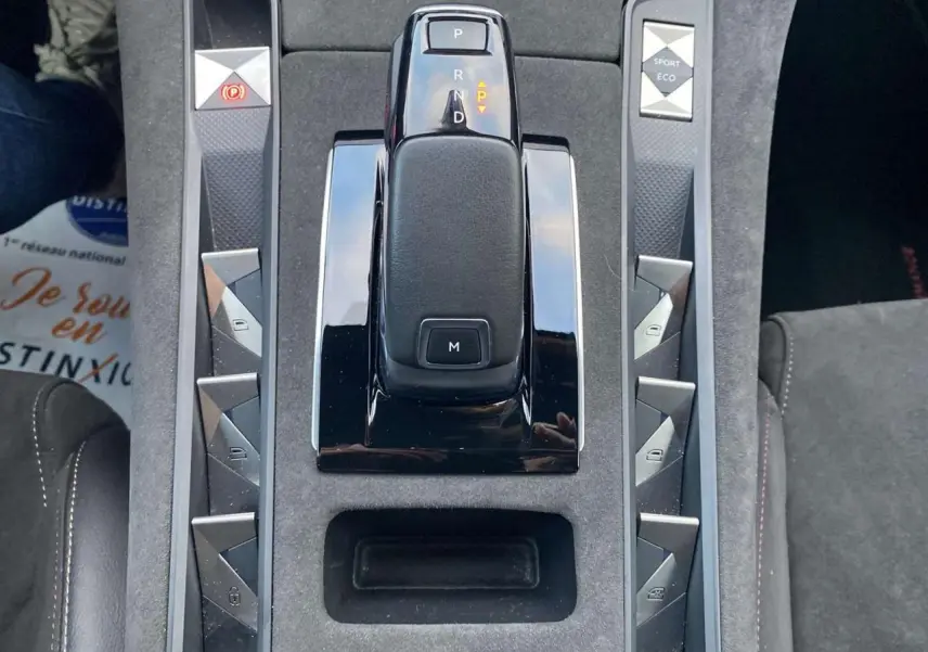 Le levier de vitesses automatique noir au centre de la console centrale grise du DS7 Crossback blanc, avec boutons triangulaires argentés.