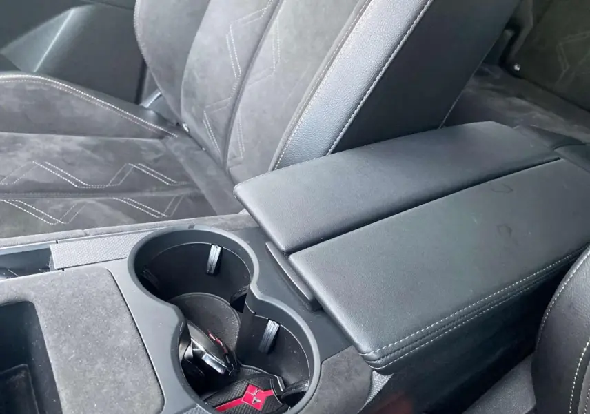 Gros plan sur l'accoudoir central noir et les sièges en alcantara gris du DS7 Crossback blanc 2022 Performance Line.