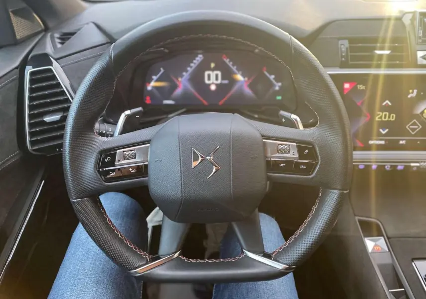 Vue rapprochée du volant DS du DS7 Crossback 2022, avec commandes intégrées et tableau de bord digital lumineux.