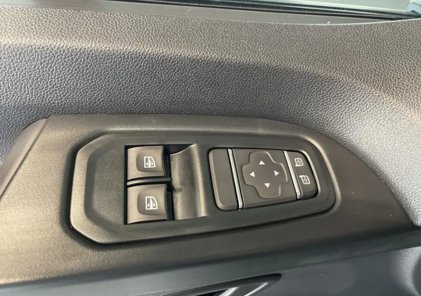 Gros plan sur les commandes de lève-vitres et réglage des rétroviseurs côté conducteur du Renault Trafic Fourgon gris Comète.