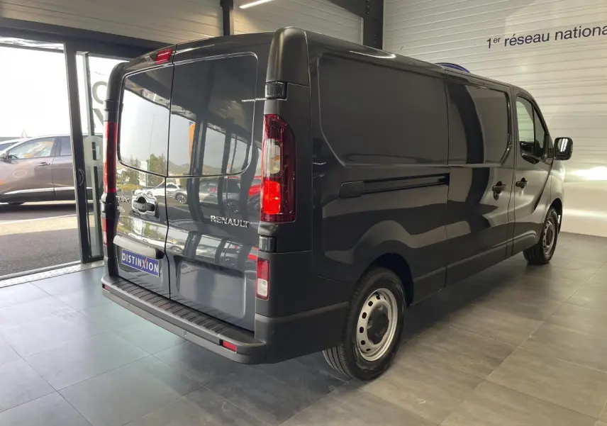 Vue 3/4 arrière droite du Renault Trafic Fourgon L2H1 2025 en gris comète, avec portes arrière fermées et jantes tôlées.
