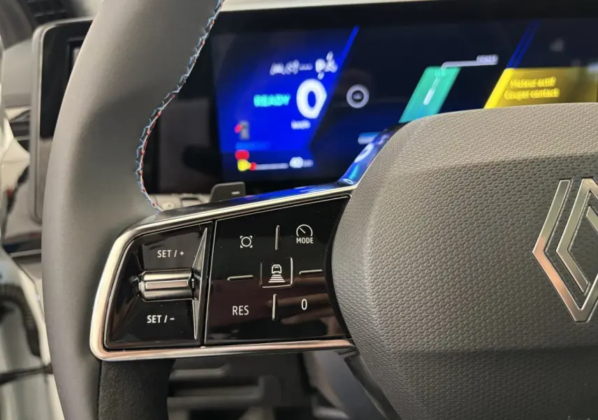 Gros plan sur le volant en cuir suédé avec commandes multifonctions du Renault Espace blanc, affichage numérique en arrière-plan.