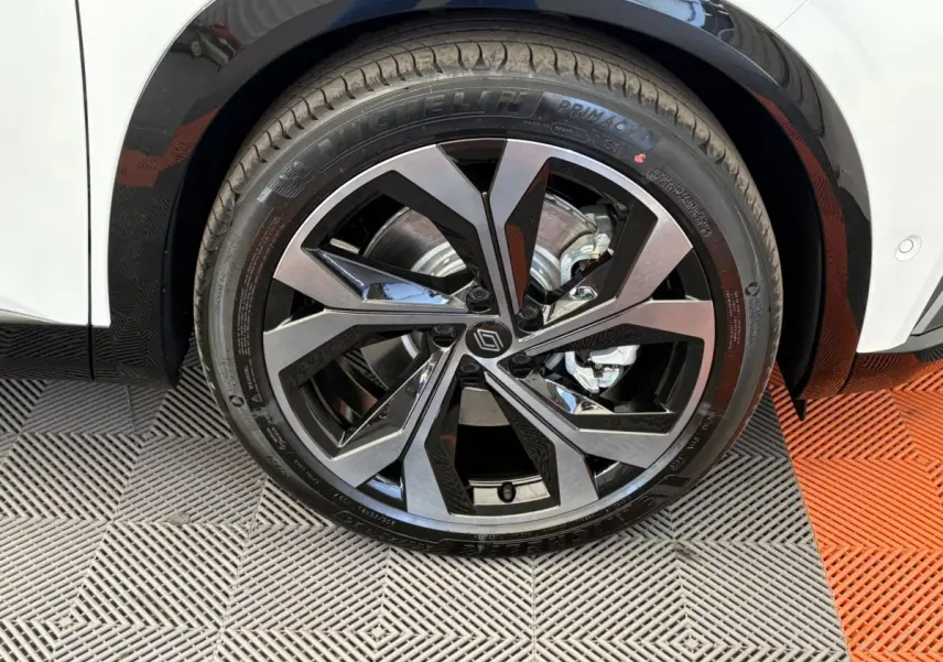 Gros plan sur la roue avant droite d’un Renault Espace blanc, jante alliage noire et argentée au design moderne.