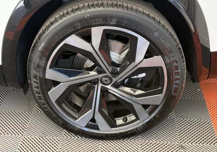 Gros plan sur la roue avant droite d’un Renault Espace blanc, avec jante alliage noire et argentée au design moderne.