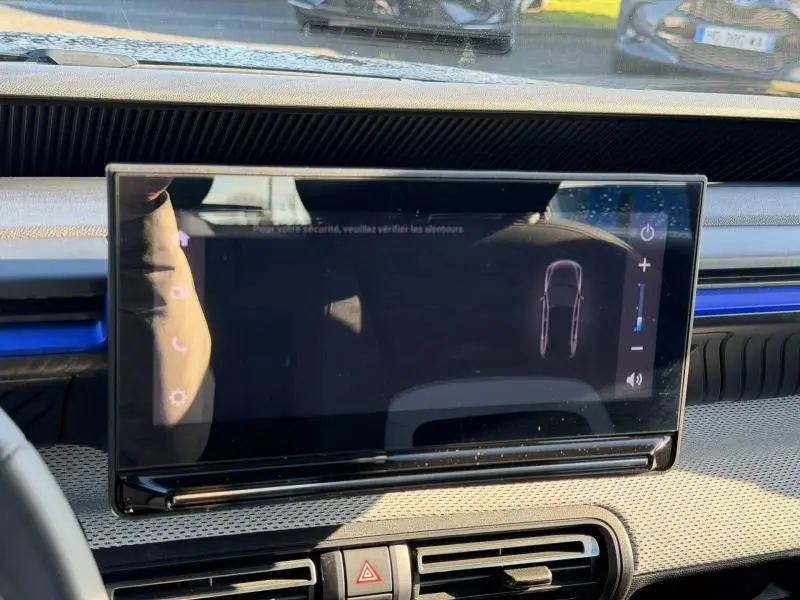 Écran tactile central du tableau de bord de la Citroën C3 2025, avec bandeau décoratif bleu visible en arrière-plan.