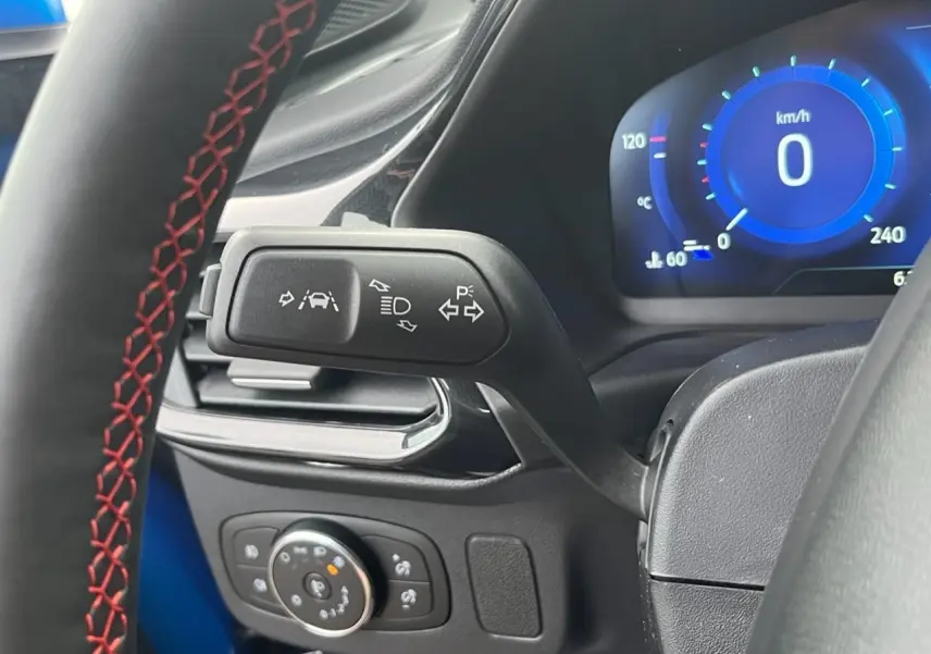 Gros plan sur la commande de clignotants et tableau de bord numérique bleu du Ford Puma 2022 côté gauche du volant.