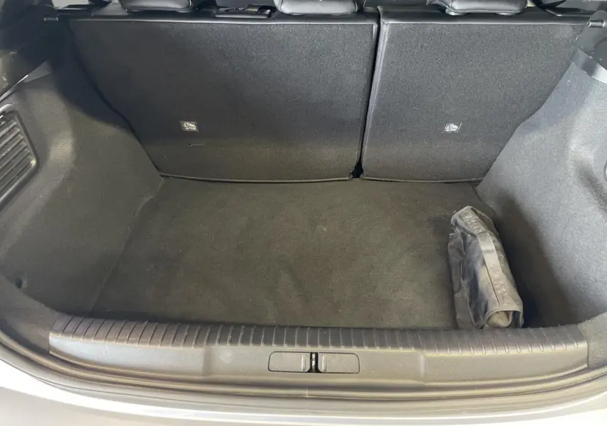 Coffre ouvert vu de dessus d'un DS3 Crossback gris Artense, avec tapis noir et pochette rangée à droite.