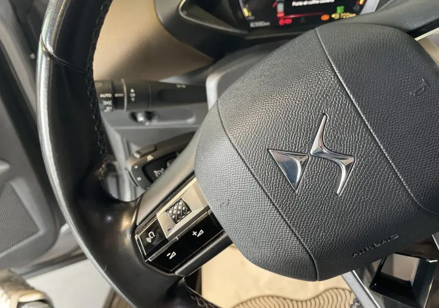 Gros plan sur le volant noir en cuir avec logo DS du DS3 Crossback 1.5 BlueHDi, intérieur beige visible en arrière-plan.