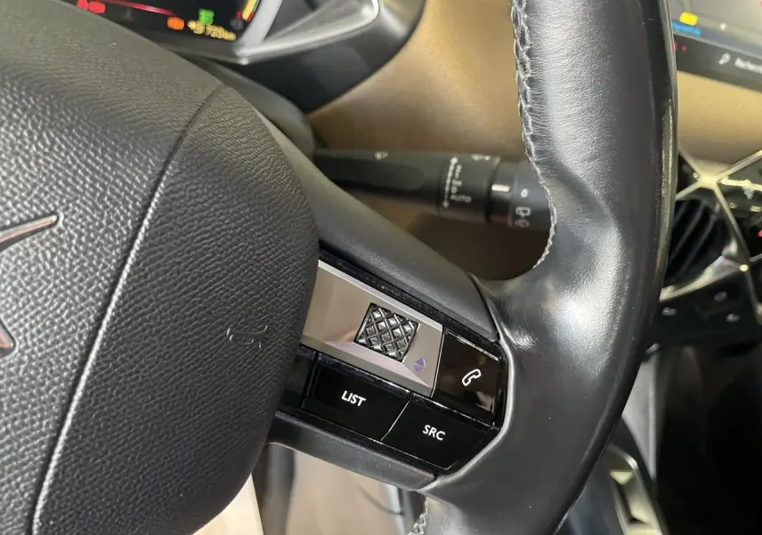Gros plan sur le volant en cuir noir du DS3 Crossback 1.5 BlueHDi avec commandes intégrées côté gauche.
