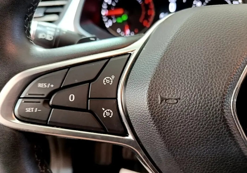 Gros plan sur les commandes du régulateur de vitesse à gauche du volant noir du Renault Captur Business 2021.
