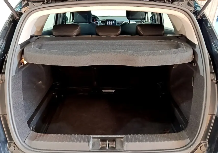 Coffre ouvert vu de l'arrière d'un Renault Captur Business noir, avec tablette cache-bagages et sièges arrière visibles.