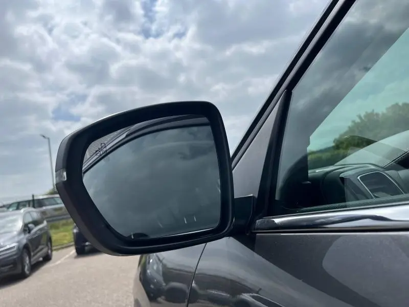 Rétroviseur extérieur côté gauche du Citroën C5 Aircross gris acier, avec vitrage latéral et ciel nuageux en reflet.