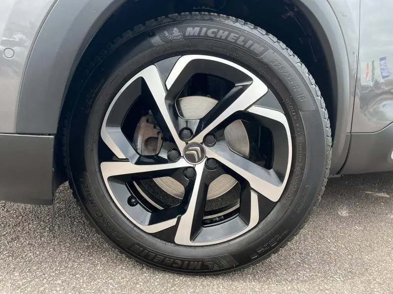 Gros plan sur la roue avant gauche du Citroën C5 Aircross gris acier avec jante alliage bi-ton et pneu Michelin.