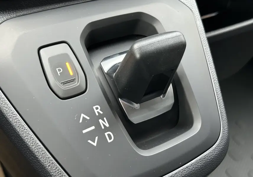 Gros plan sur le levier de vitesses automatique et le bouton de stationnement du Renault Trafic Fourgon gris, intérieur moderne.