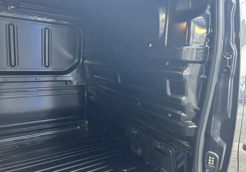 Vue intérieure de la zone de chargement du Renault Trafic Fourgon gris Comète, montrant la paroi et le plancher métalliques.