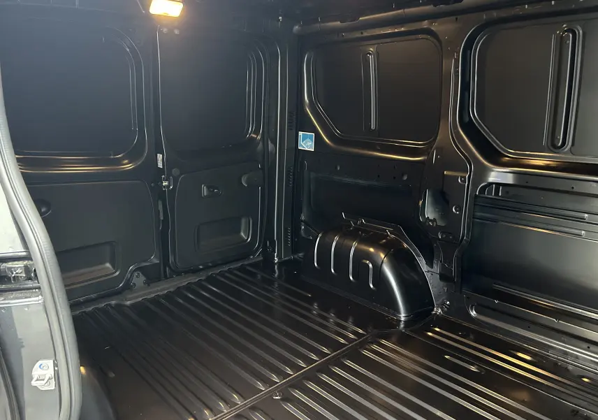Intérieur du coffre arrière du Renault Trafic Fourgon gris Comète, vue de profil droit montrant l’espace de chargement vide.